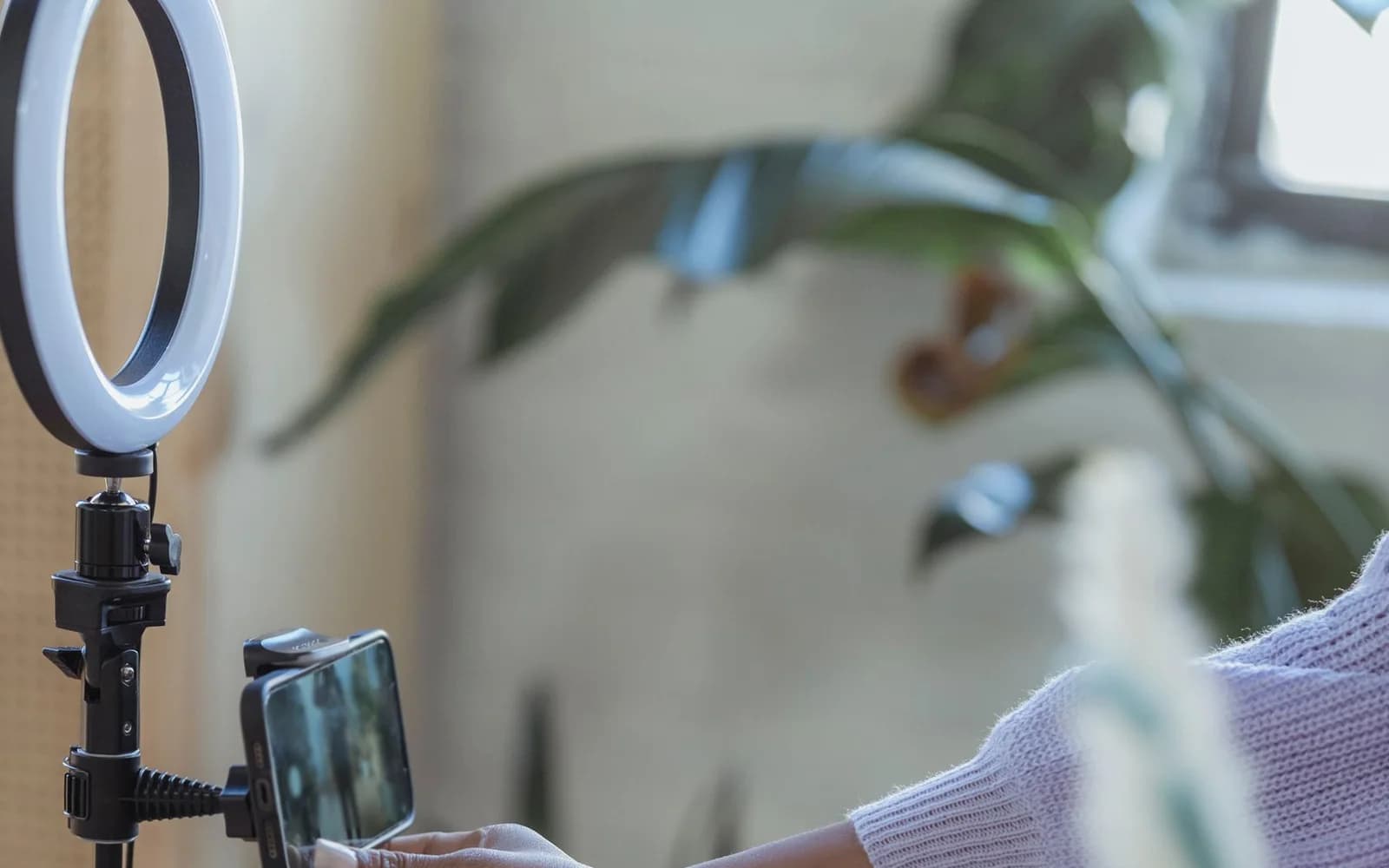 Editorial photograph: Black woman using smartphone on tripod with ring lamp