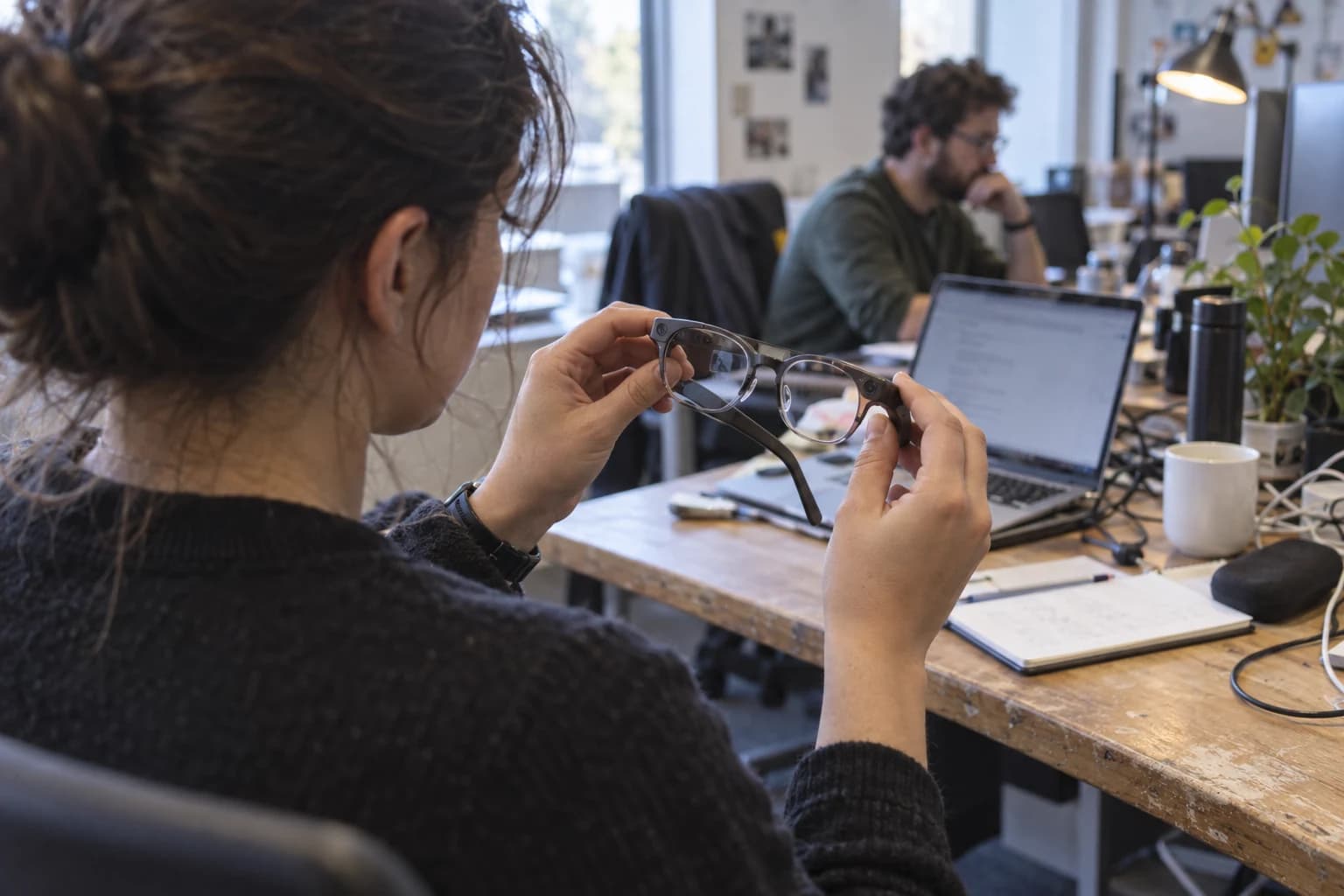 Ilustración asistida por IA de una persona examinando gafas inteligentes genéricas; no es un producto de Meta
