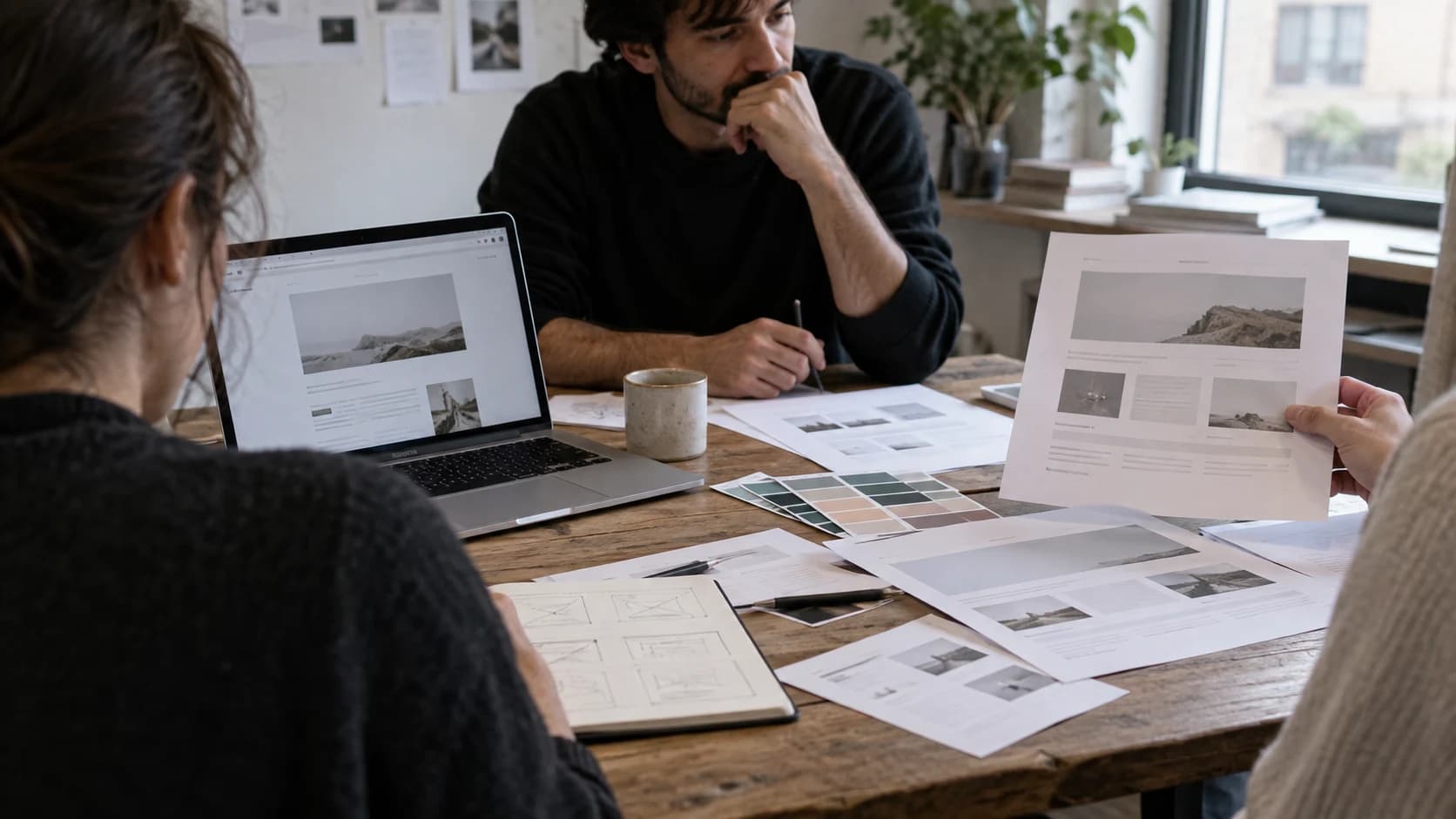 AI-assisted editorial image of a design team reviewing printed website layouts and colour samples; not a Framer interface