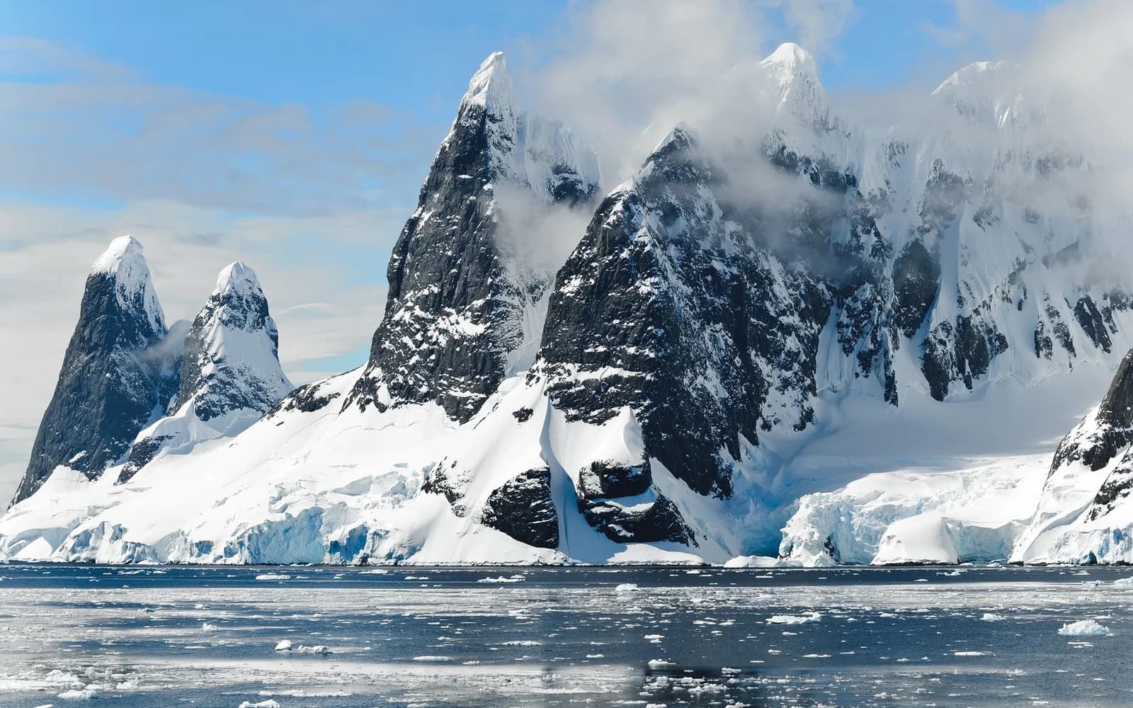 Snow-covered mountains above icy Antarctic water; an illustrative photograph without the IceCube observatory.