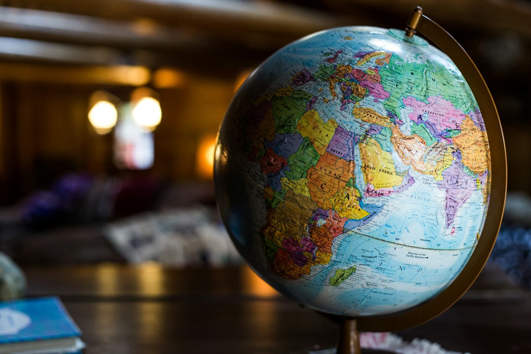 Political globe on a wooden desk in a warmly lit room, with Europe, Africa and Asia facing the camera