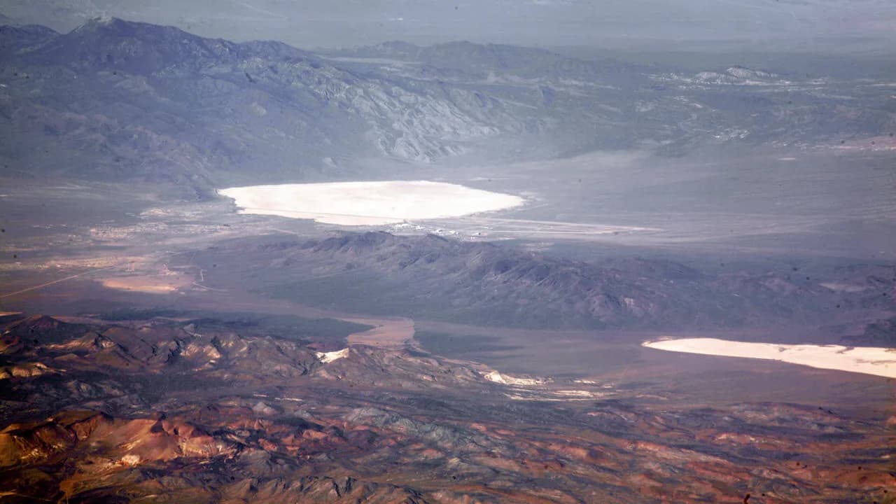 Vista aérea del desierto de Nevada con dos lechos de lago secos y claros, Groom Lake y Papoose Lake, entre sierras pardas