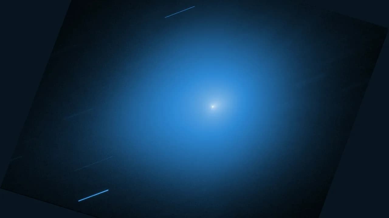 Imagen del telescopio Hubble del cometa interestelar 3I/ATLAS: un núcleo brillante dentro de un halo azul y estelas de estrellas