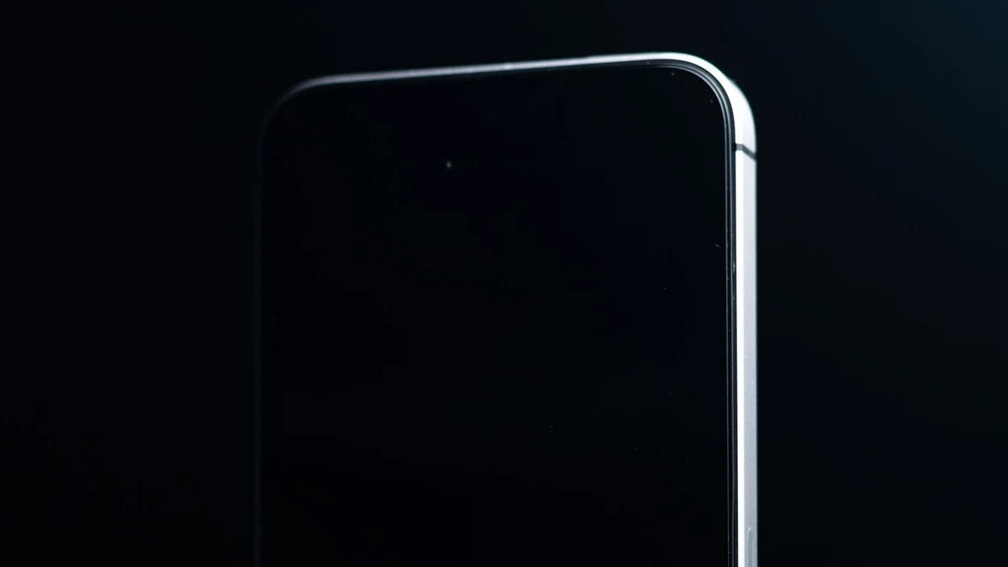 The top edge of a dark smartphone outlined by a thin line of light against a black background; illustrative photo, not an iPhone 18 Pro