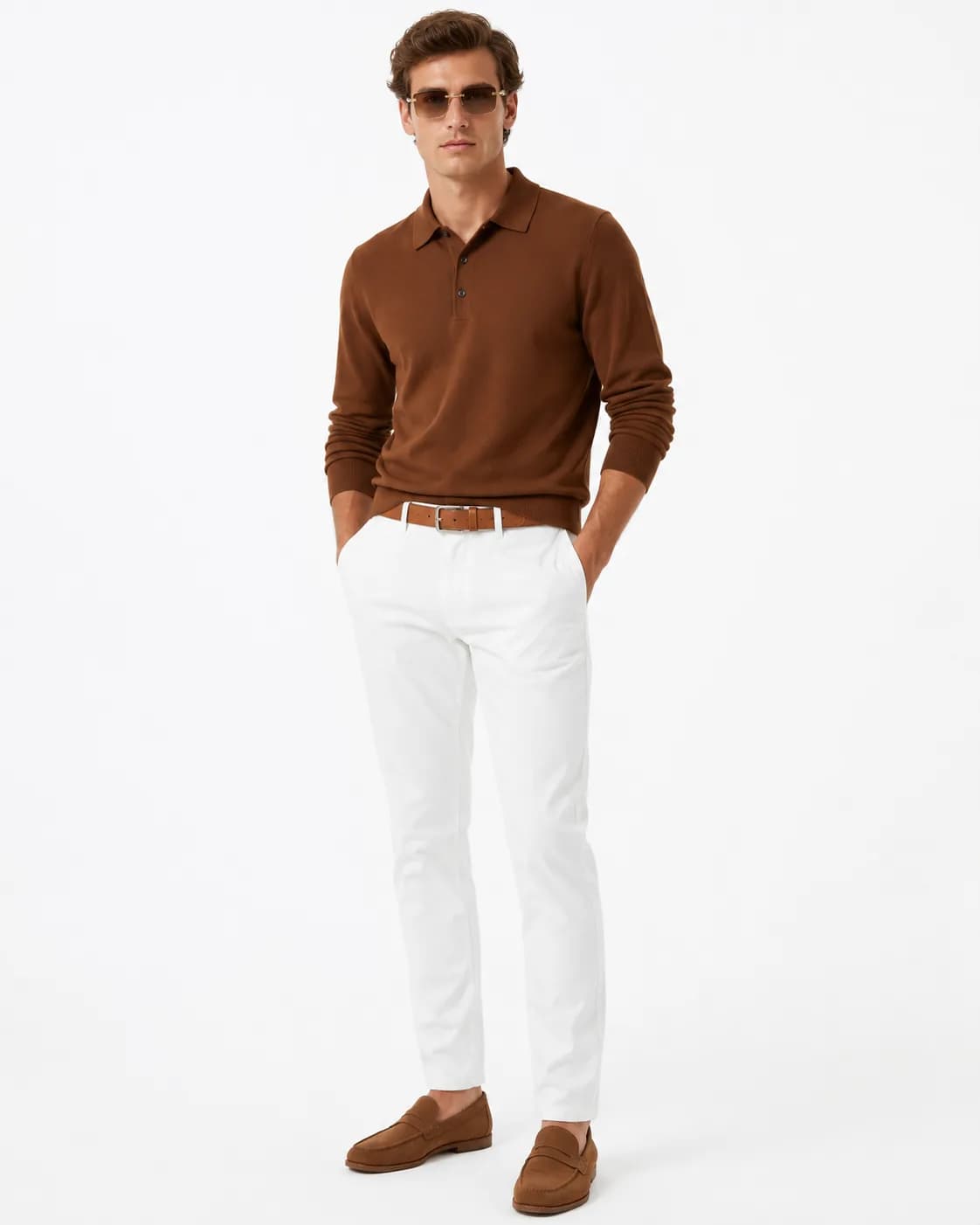 Man in a cocoa knit polo, white chinos, a cognac belt and amber sunglasses on a white background
