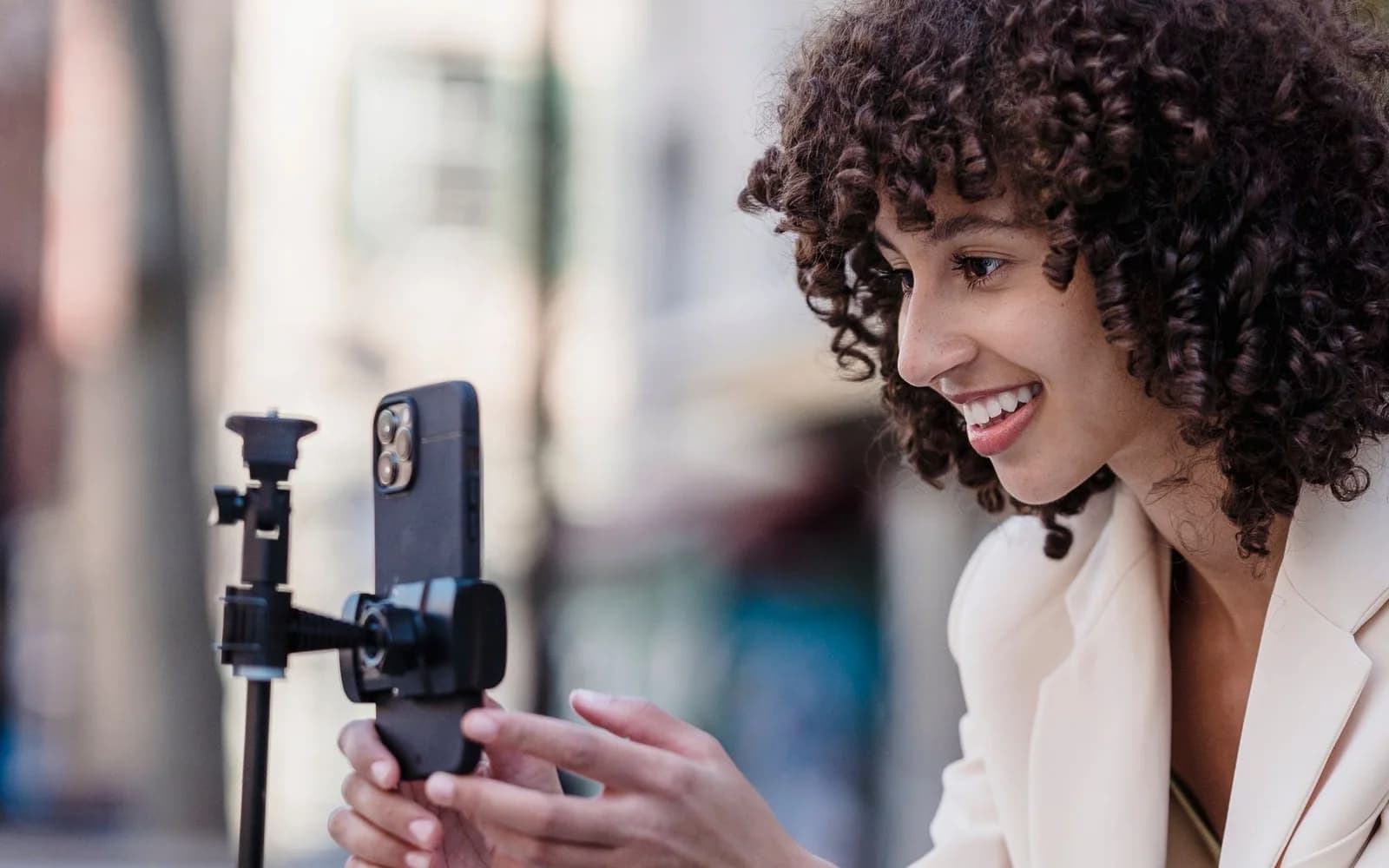 Editorial photograph: Smiling ethnic woman recording video on smartphone