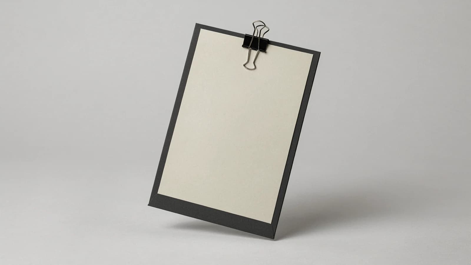 A blank cream sheet held by a black binder clip on a dark board, standing on a plain light grey background; AI-generated image