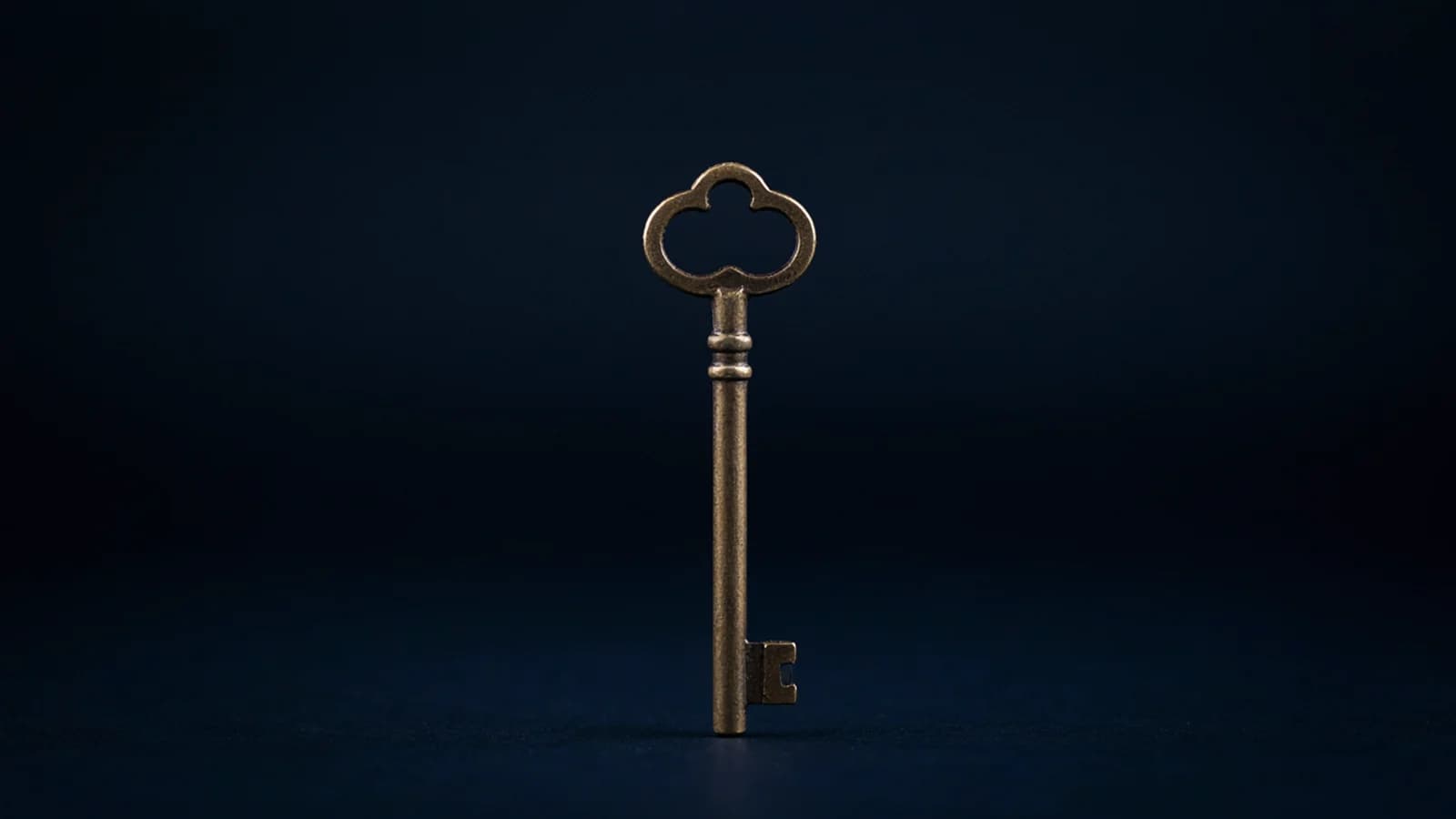An old brass key standing upright on a plain deep navy background; AI-generated image