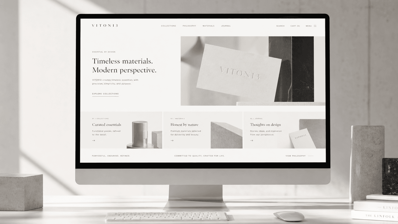 A desktop monitor on a pale desk shows the VITON13 website home page headed “Timeless materials. Modern perspective.”, with a keyboard, a mouse and concrete blocks beside it